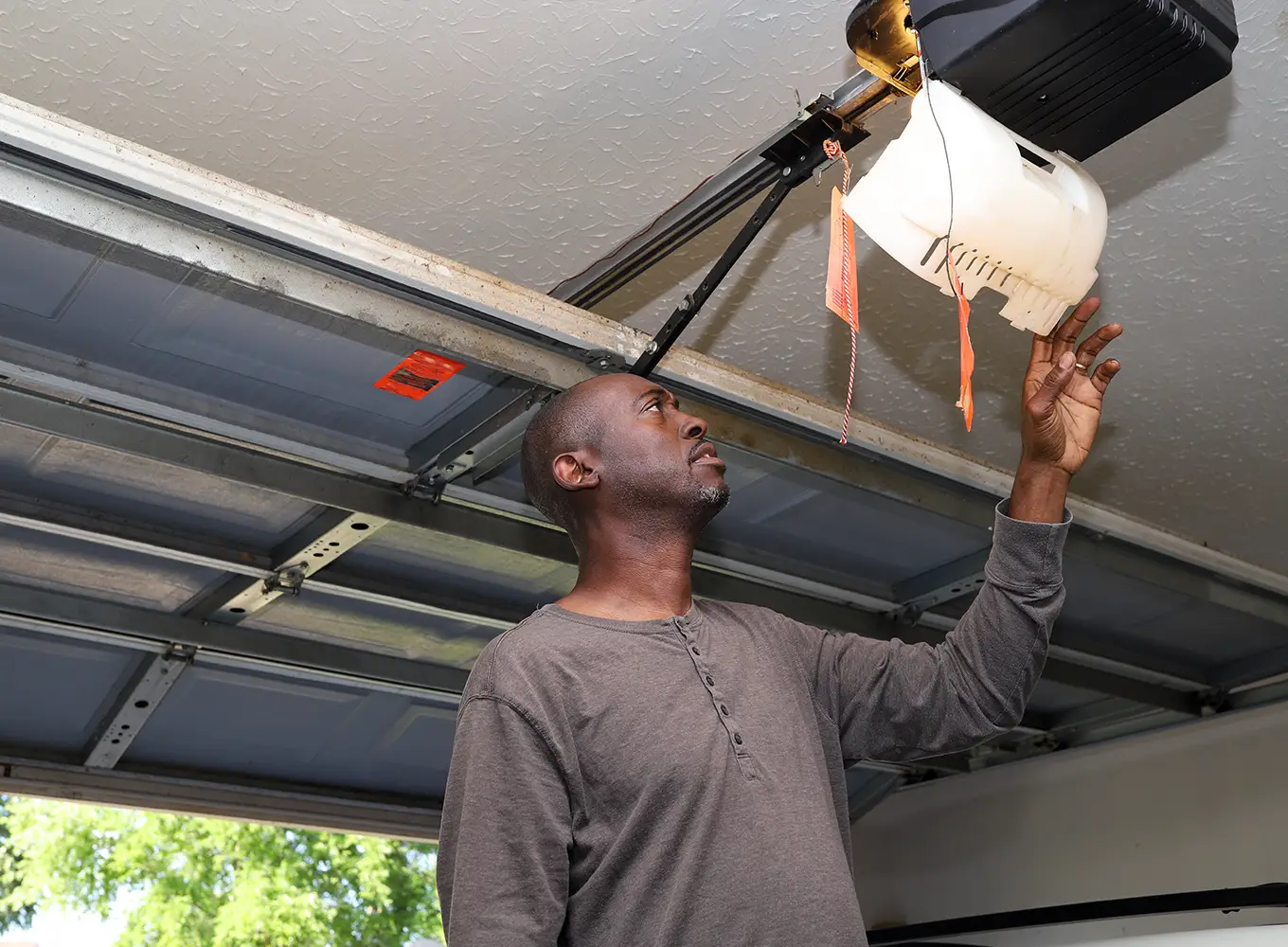 man inspecting his automatic garage door opener to see if it needs repairing